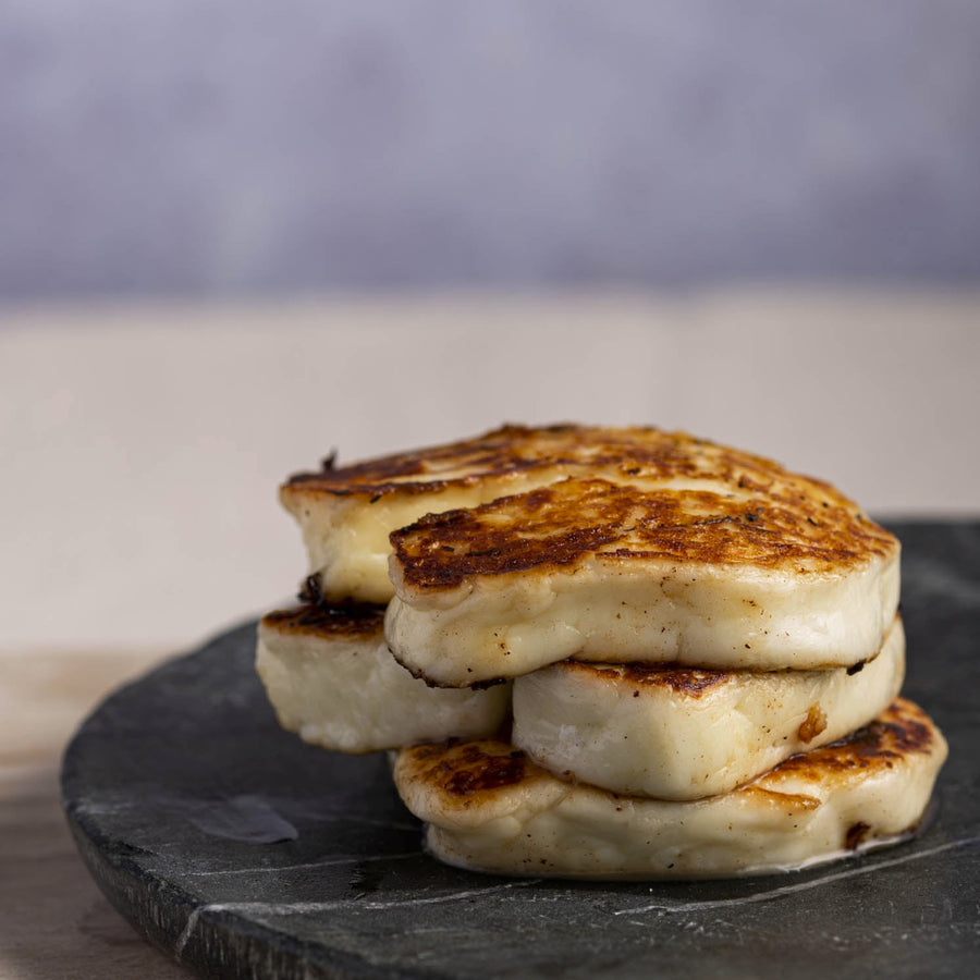 Pieces of fried halloumi stacked up on a slate platter.