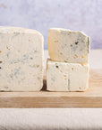 Cut pieces of harbourne blue cheese on a wooden board.