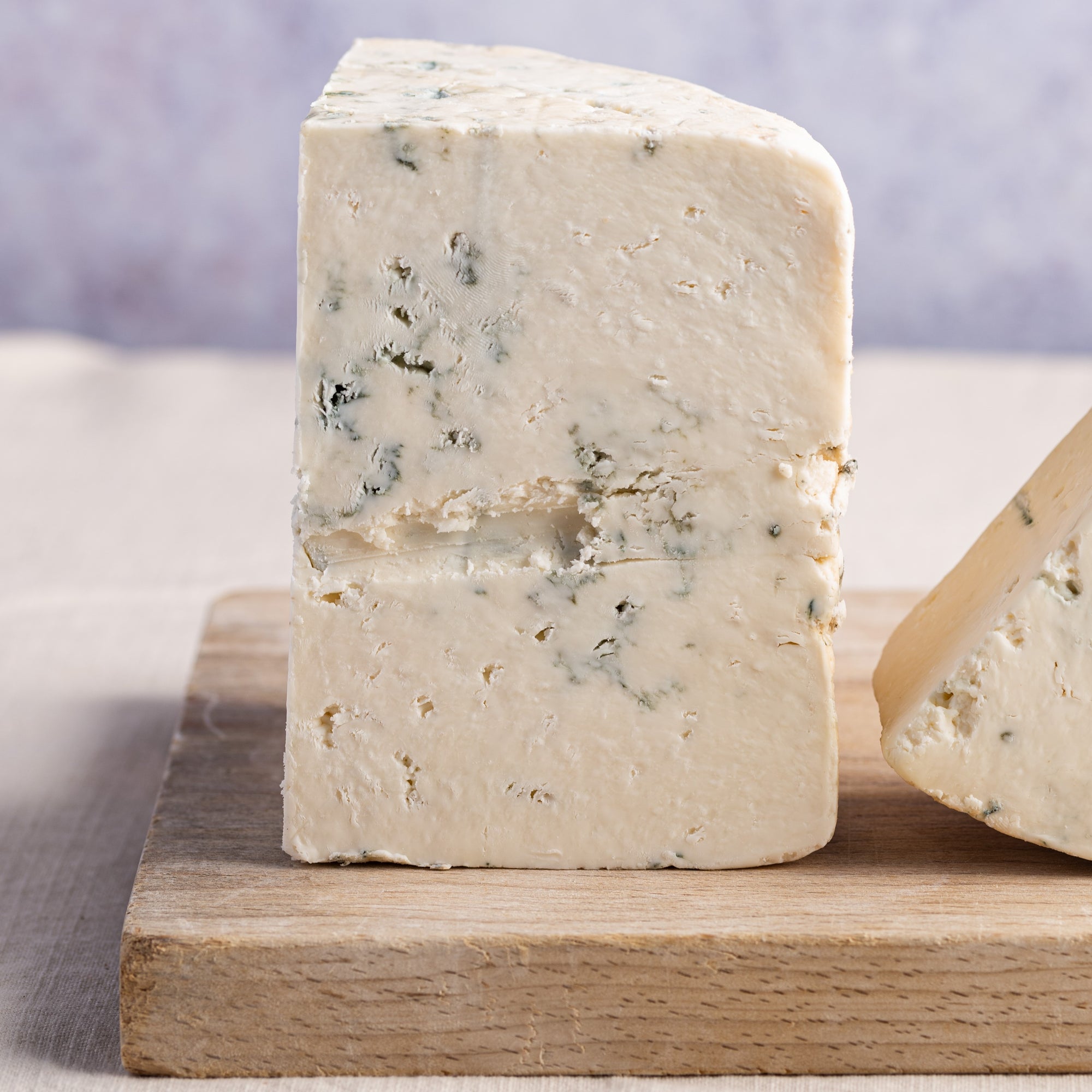 Close up of the cut side of a piece of Harbourne Blue cheese on a wooden board.