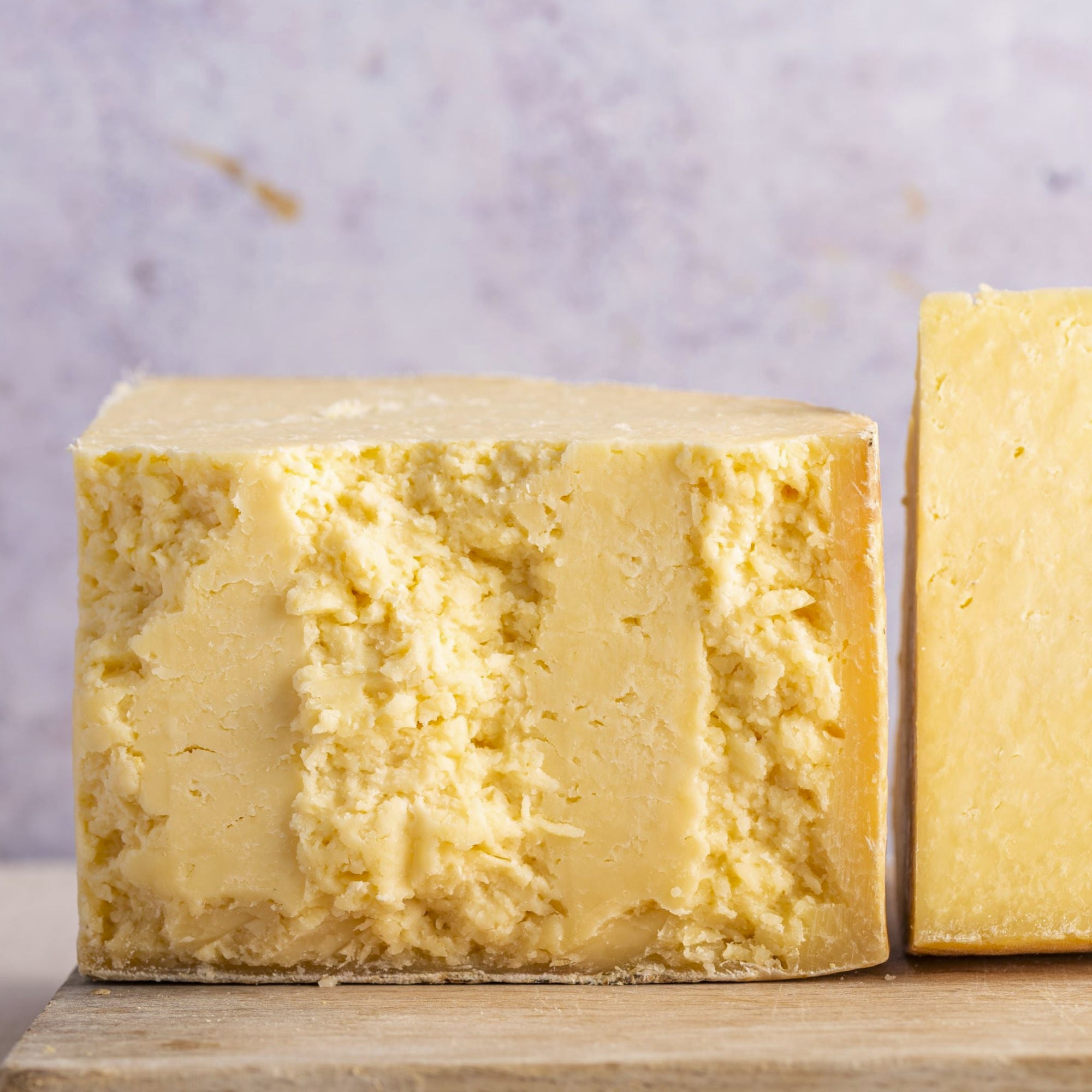 A large piece of Lancashire cheese on a wooden board.