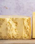 A large piece of Lancashire cheese on a wooden board.