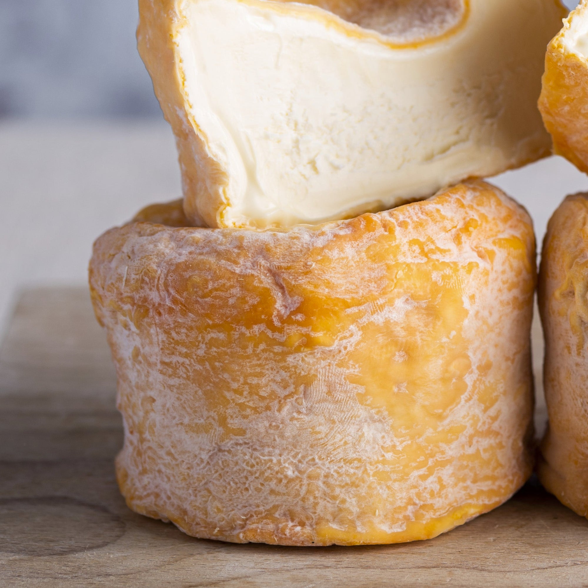 Close up of cut and whole Langres cheese on a wooden board.