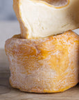 Close up of cut and whole Langres cheese on a wooden board.