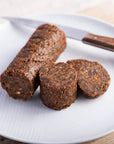 Cuts of lonzino di fico and a sharp knife on a white plate.