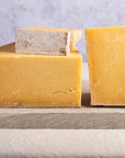 Various cuts of Montgomery's Cheddar on a wooden board.