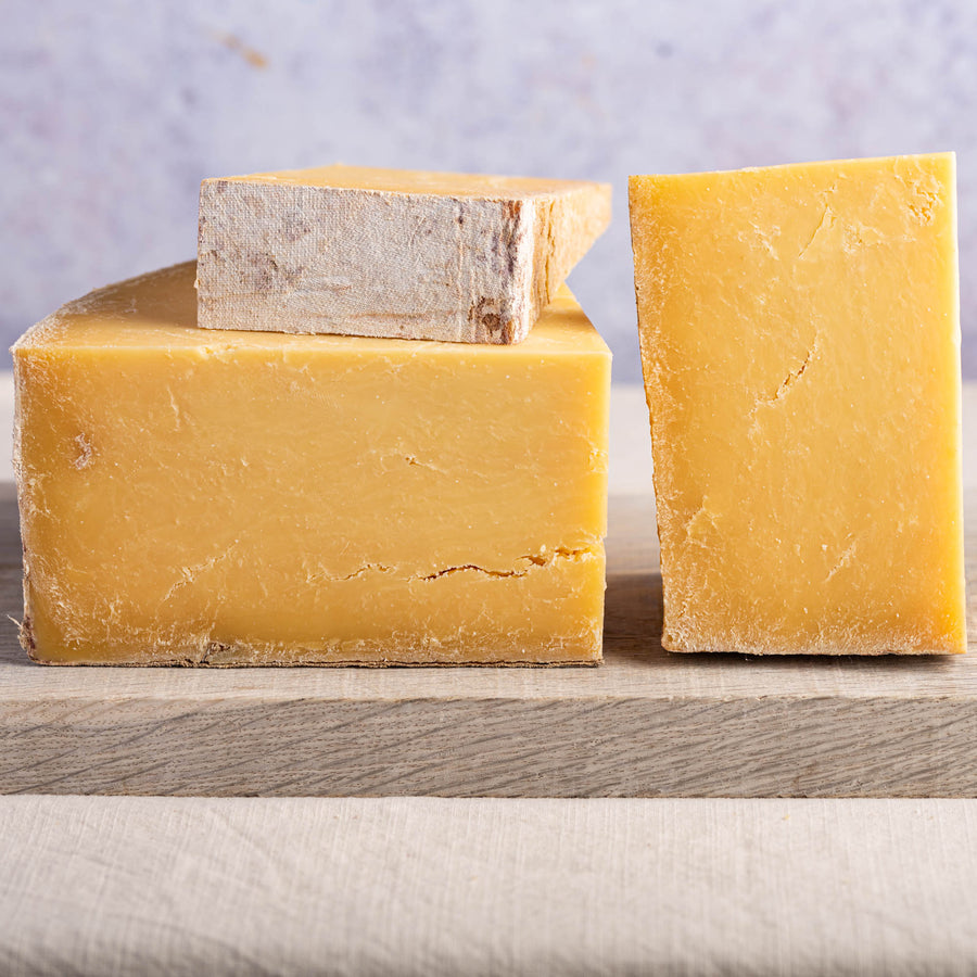 Various cuts of Montgomery's Cheddar on a wooden board.