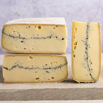 Cuts of morbier cheese arranged on a wooden board.