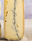 A piece of Morbier cheese, with its distinctive layer of ash, arranged on a wooden board.