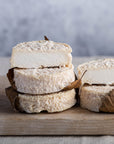 Cut and whole pieces of Mothais sur Feuille goat's cheese on a wooden board.