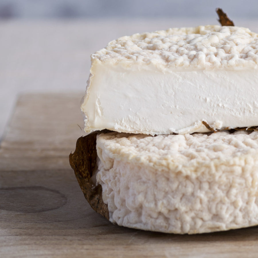 A Mothais sur Feuille goat's cheese on a wooden board.