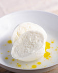 A cut Mozzarella cheese on a plate drizzled with some olive oil.