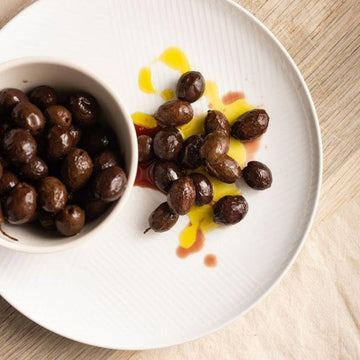 Black nyons olives in a bowl and on a white plate.
