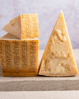 Cut pieces of parmigiano cheese on a wooden board.