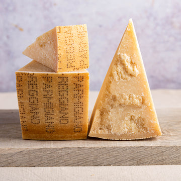 Cut pieces of parmigiano cheese on a wooden board.