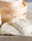 Cut pieces of soft, unctuous Perail ewe's milk cheese on a wooden board.