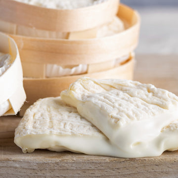 Cut pieces of soft, unctuous Perail ewe's milk cheese on a wooden board.