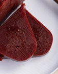 Slices of crimson quince paste on a white plate.