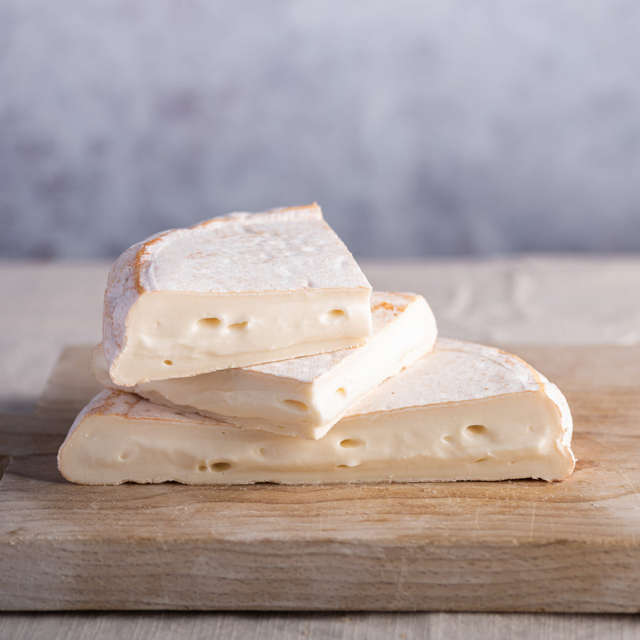 Cuts of Reblochon cheese on a wooden board.