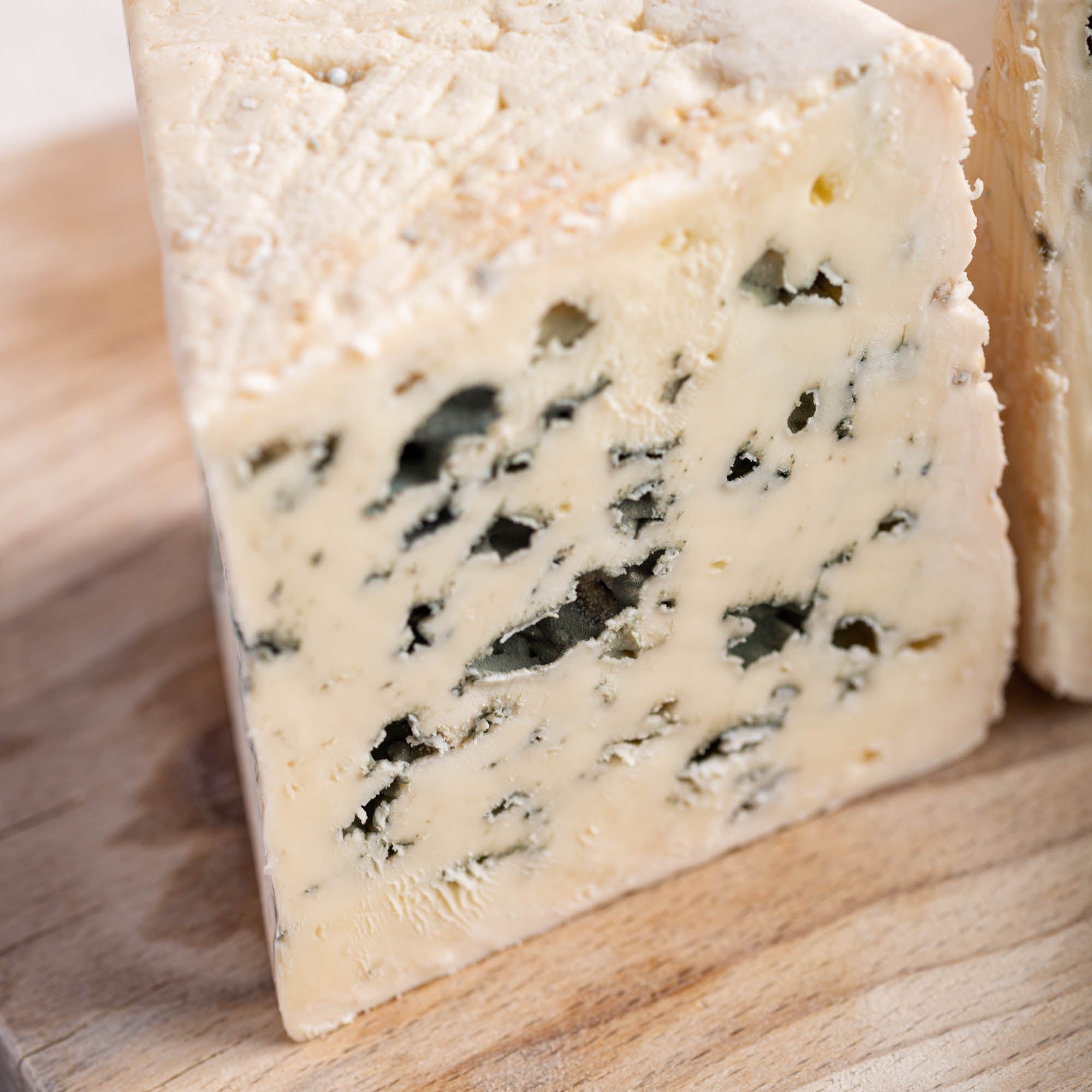 A cut piece of roquefort cheese on a wooden board.