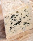 A cut piece of roquefort cheese on a wooden board.