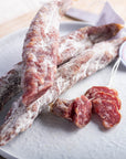 Slices and whole French saucisse seche salamis on a white plate.