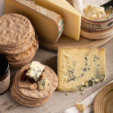 A selection of biscuits and cheese on a wooden board.