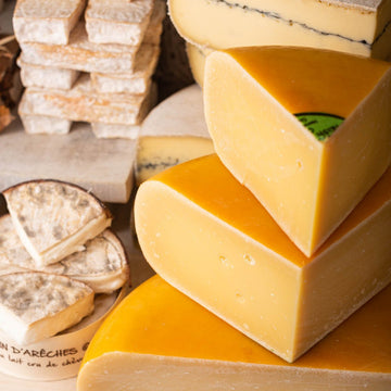 Large and small cuts of cheese on a shop counter.