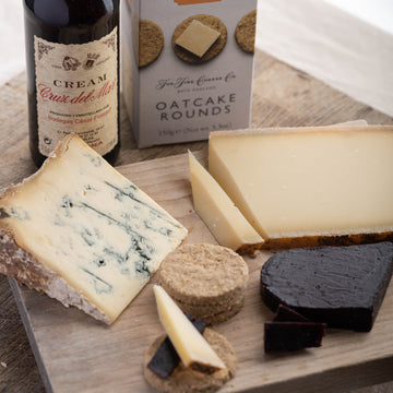 A selection of cheese, biscuits and sherry on a wooden board