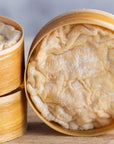 A close up of the orange wrinkly rind of St. Cera cheeses in their round wooden boxes, stacked up on a wooden board.