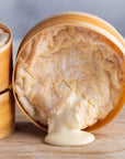 An oozing soft St. Cera cheese on a wooden board.