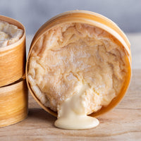 An oozing soft St. Cera cheese on a wooden board.