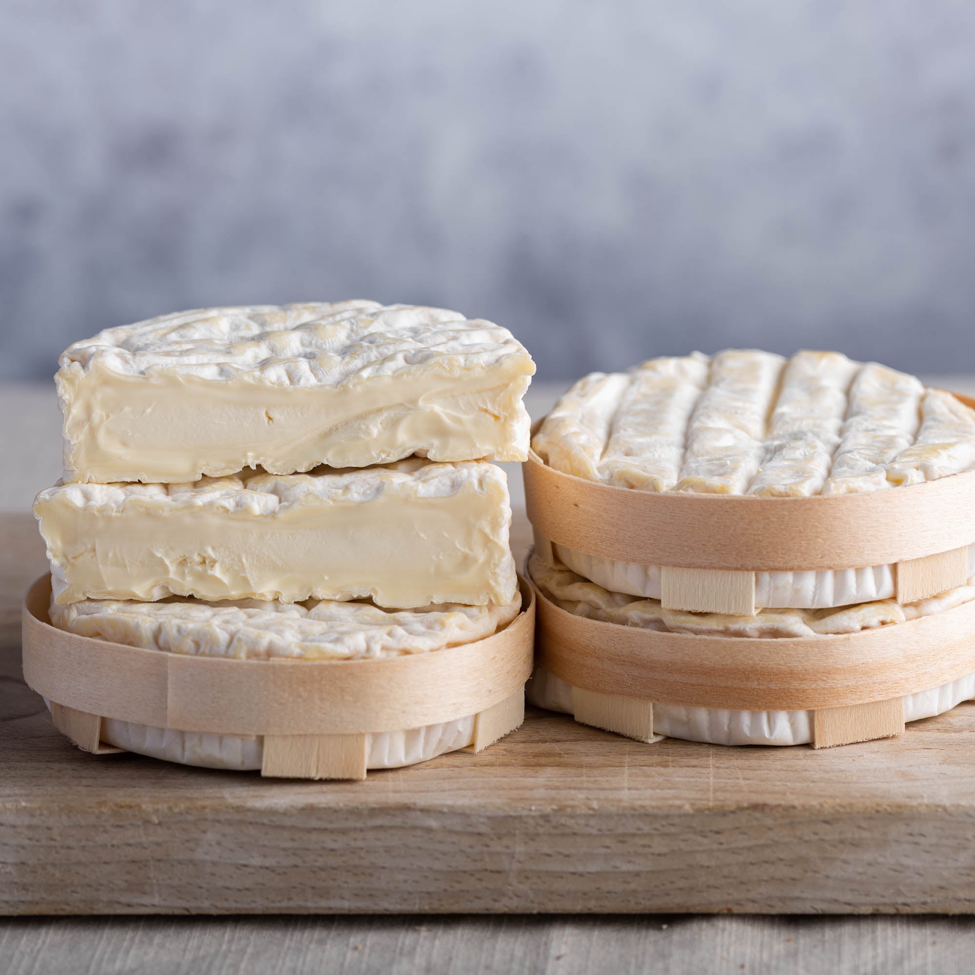 Cut and whole st felicien cheese in their baskets on a wooden board.