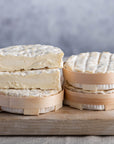 Cut and whole st felicien cheese in their baskets on a wooden board.