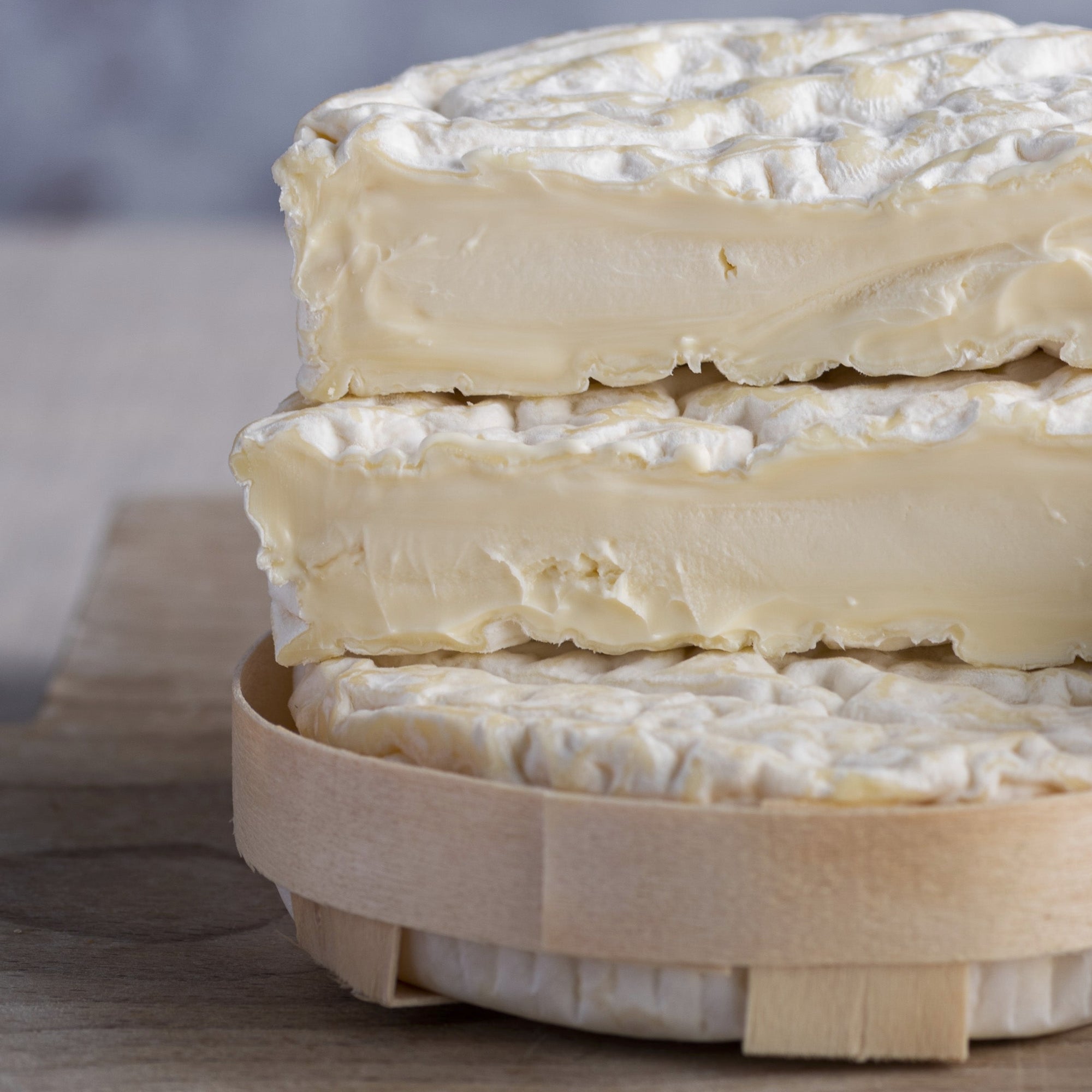 The cut faces of a St. Felicien cheese on a wooden board.