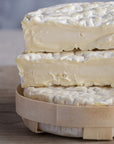 The cut faces of a St. Felicien cheese on a wooden board.