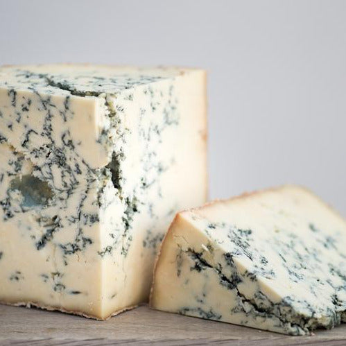 Cuts of Stilton blue cheese on a wooden board.